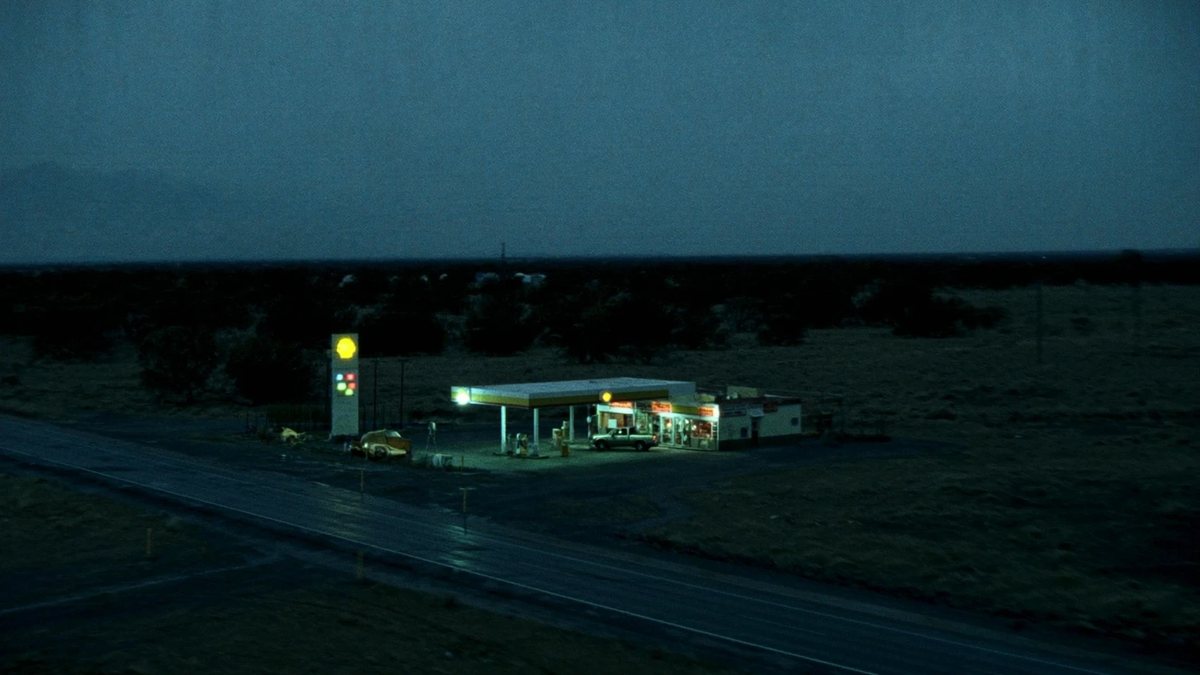 The Other Shift key art: a lone petrol station lit up beside a highway at dusk